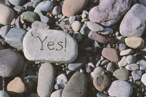 Fotografi Flat stone with the word Yes! among other stones.