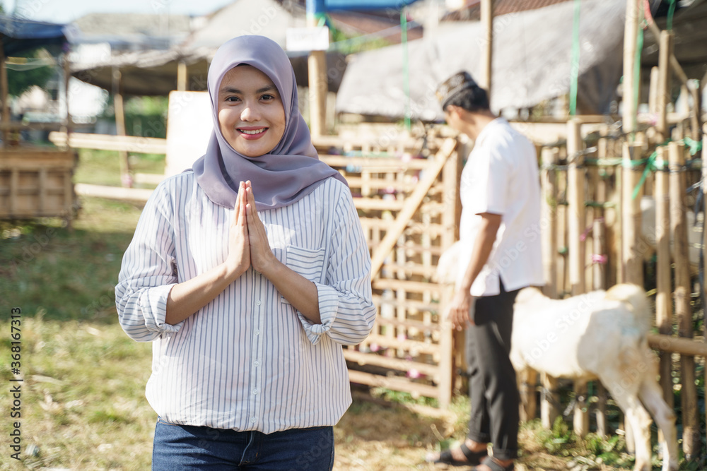 portrait of young muslim woman with goat for idul adha qurban sacrifice