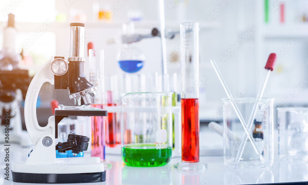 Microscope and test tubes with lab glassware in laboratory background, research and Scientific concept Microscope and test tubes with lab glassware in laboratory background, research and Scientific concept