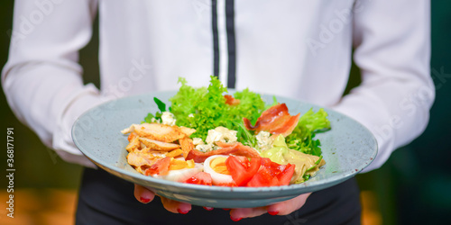 Fototapeta Naklejka Na Ścianę i Meble -  Healthy Green Organic Caesar Salad with Cheese and Croutons. Waiter in white uniform, shirt, serving caesar salad.