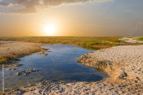 small water puddle in a prairie at the sunset