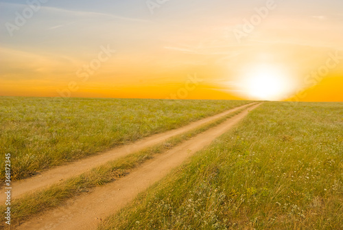 ground road among a prairie at the sunset