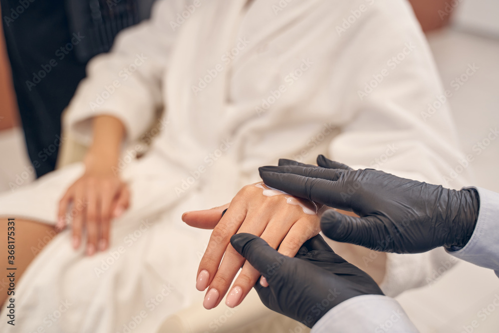 Beauty specialist applying body lotion on woman skin Beauty specialist applying body lotion on woman skin