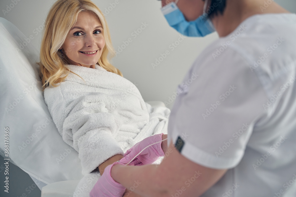 Cheerful female expecting beauty treatment in professional clinic Cheerful female expecting beauty treatment in professional clinic