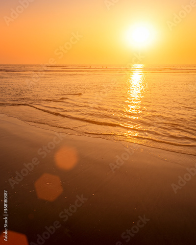 A colorful sunset or sunrise on the seaside with a sandy beach with impurities of volcanic ash. Mandrem, Goa, India. photo