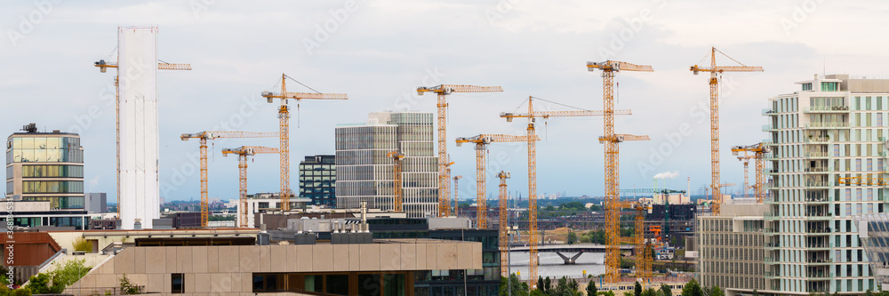 Panorama with numerous construction cranes. Symbol for construction industry and city development. Panorama with numerous construction cranes. Symbol for construction industry and city development.