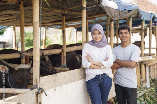 happy man and woman standing in the farm. eid adha sacrifice concept