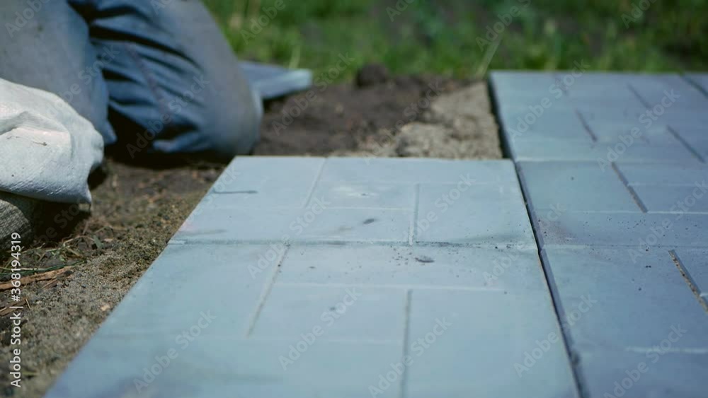 Man lays a gray paving tile. Man lays a gray paving tile.