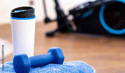 Sports background with blue accent. Close-up on a glass of water, a dumbbell and a towel. Sports at home, attributes for sports. Active lifestyle.
 photo