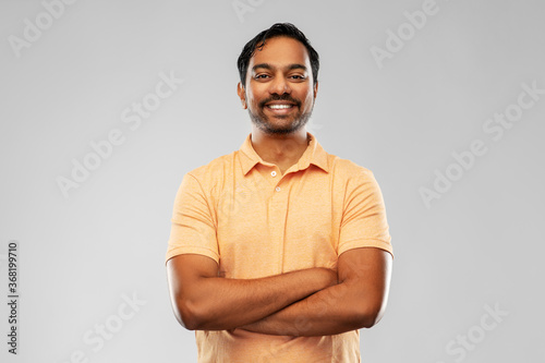 people and furniture concept - portrait of happy smiling young indian man with crossed arms over grey background