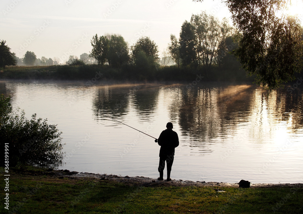 Fisherman catches fish with a fishing rod in the early morning
