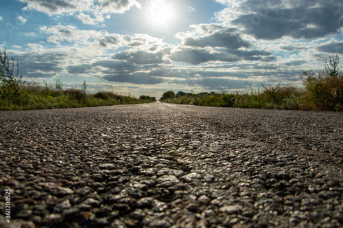 Asphalt road goes to the horizon, against the background of the sun, sunset