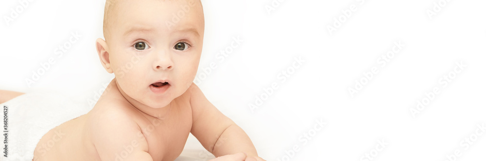 Little pretty kid. Lying at home. White background. Happy expression. Male child portrait. Mother care. Wearing diaper. Funny sensitive human. Horizontal banner with copyspace. Look at camera Little pretty kid. Lying at home. White background. Happy expression. Male child portrait. Mother care. Wearing diaper. Funny sensitive human. Horizontal banner with copyspace. Look at camera