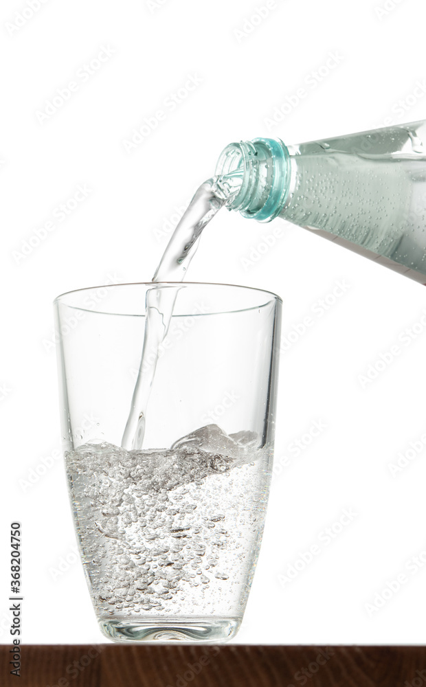 Pouring water into glass on table with isolated background Pouring water into glass on table with isolated background