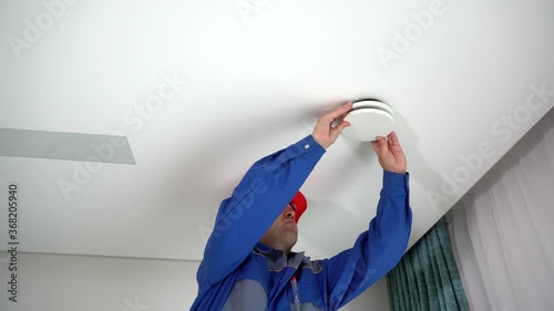 Skilled specialist man inspect air diffuser mounted on ceiling. Fresh air supply photo