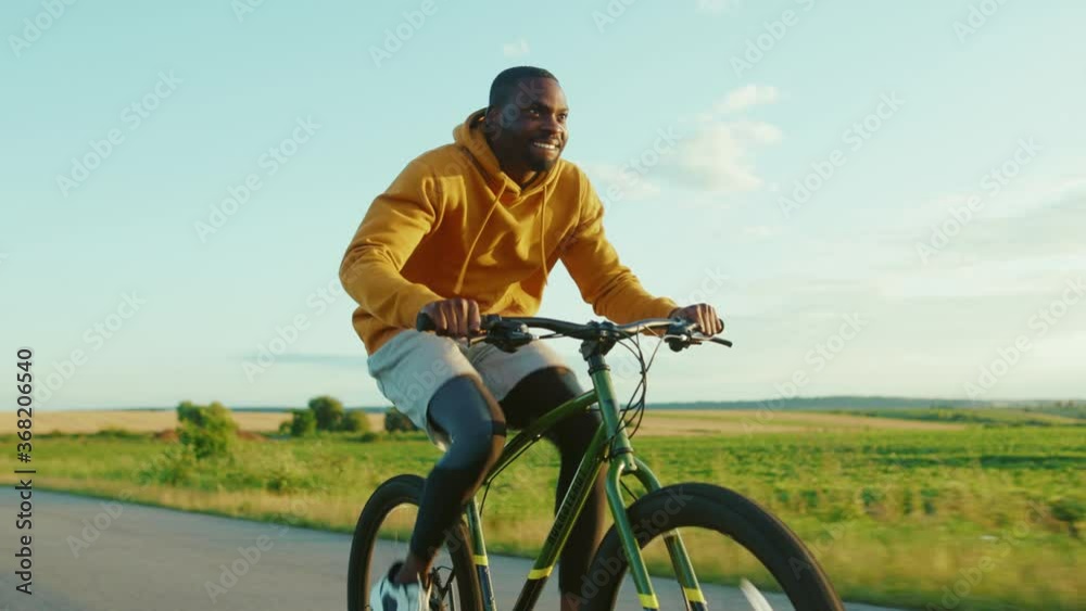 Funny smiling african american man in cycling on road in the countryside bicycle happy bike biking portrait active raised relax ride sunshine slow motion Funny smiling african american man in cycling on road in the countryside bicycle happy bike biking portrait active raised relax ride sunshine slow motion