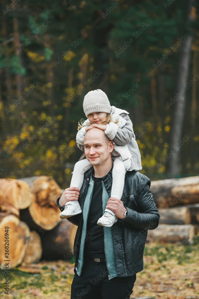 Fototapeta premium Handsome bald father and his small daughter in a autumn forest.