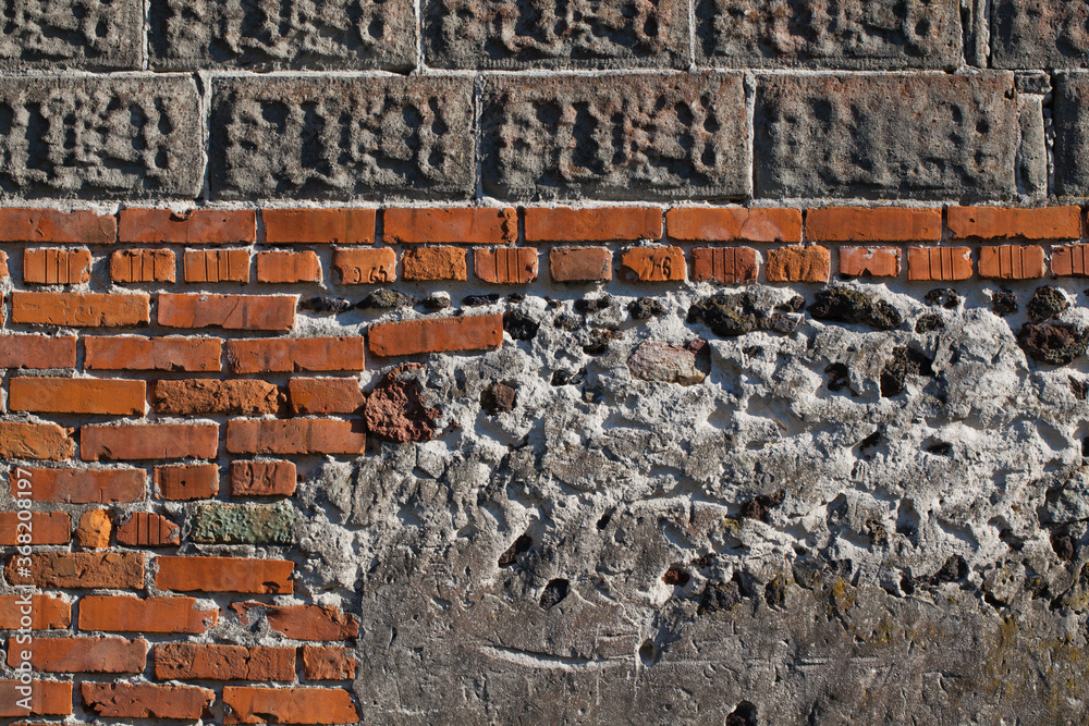 Obraz premium Skała osadowa, ruda darniowa, wmurowana we fragment ceglanej zewnętrznej ściany budynku, fragment.