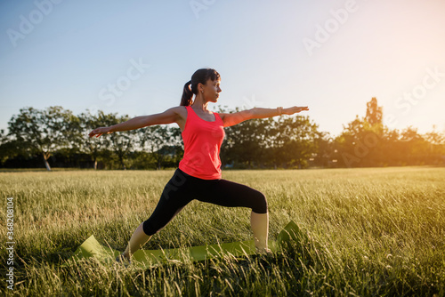 Young beautiful woman is making sport, she is doing the yoga exercises on a grass in the midst of nature on sunset. © Med Photo Studio