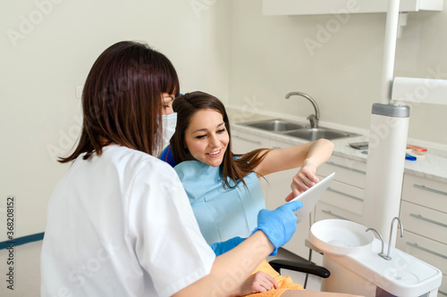 Young woman dentist showing to her patient a digital dental x ray on a tablet in dentistry