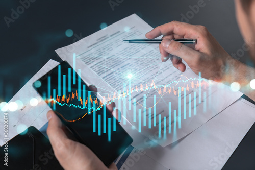 Multi exposure of man signing contract with phone and forex chart hologram. Concept of financial market, stock exchange, investment in bonds.