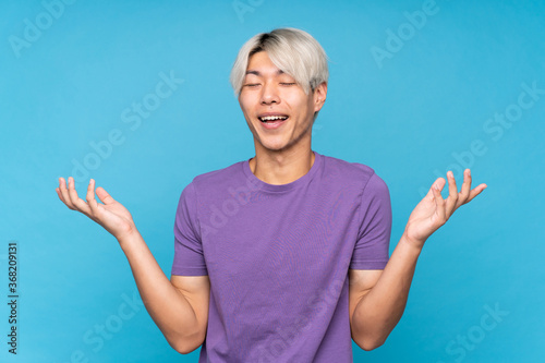 Young asian man over isolated blue background smiling a lot