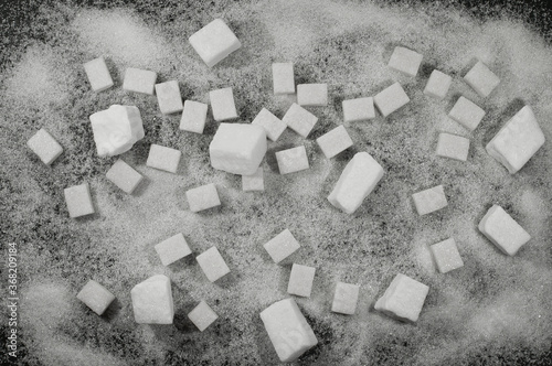 lump and granulated sugar on a black background, a source of glucose and sucrose, an additive to tea photo