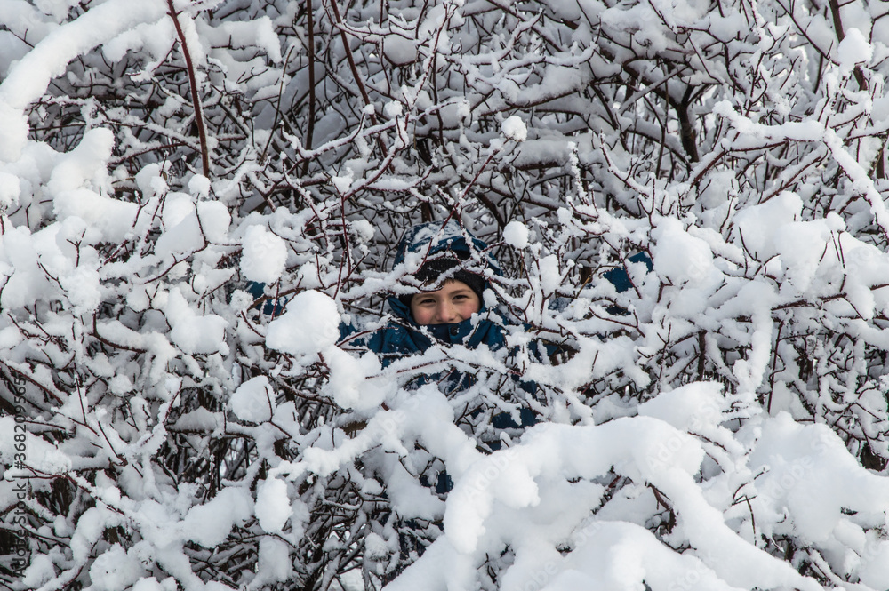 winter park, the child smiles inside a snow-covered Bush winter park, the child smiles inside a snow-covered Bush