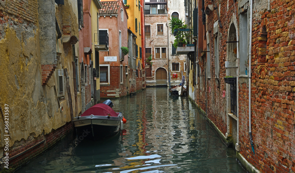 Quiet Canal in Venice with boats and crumbling walls.