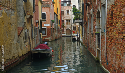 Quiet Canal in Venice with boats and crumbling walls. © harlequin9