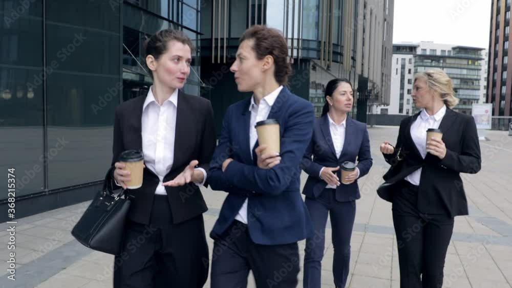 Four caucasian women business colleagues walking outdoors. Business women walking around corporate centre company building. Females bosses talking on cooperation future plans discussing Coffee break Four caucasian women business colleagues walking outdoors. Business women walking around corporate centre company building. Females bosses talking on cooperation future plans discussing Coffee break