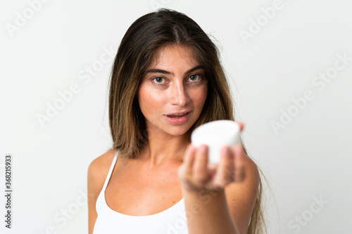 Young caucasian woman isolated on white background with moisturizer and offering it