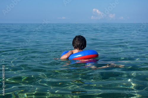 Little boy with inflatable ring swimming in the sea. Child with a floating ring enjoy in crystal clear water © Ivan