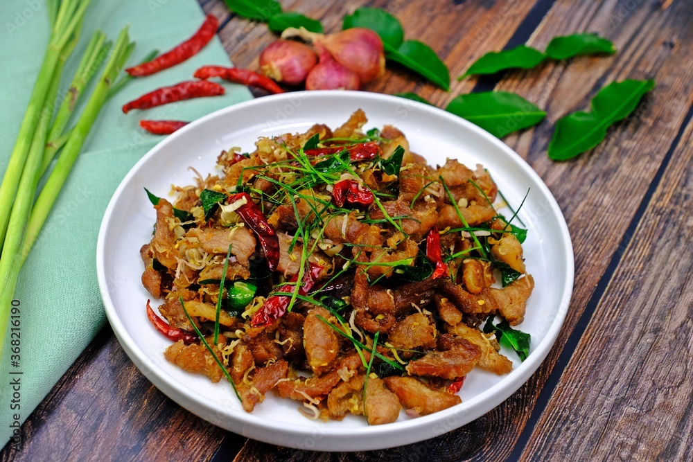Stir fry pork with lemongrass and chilli surrounded by key ingredients on wooden table. Authentic Thai food. Stir fry pork with lemongrass and chilli surrounded by key ingredients on wooden table. Authentic Thai food.