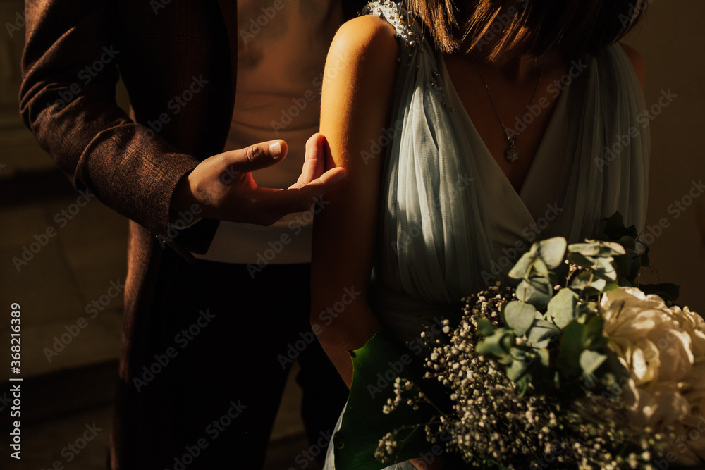 Cropped portrait of a loving couple hugging. Close up portrait of the charming newlyweds in the dark hall of the restaurant and the light of a sun.