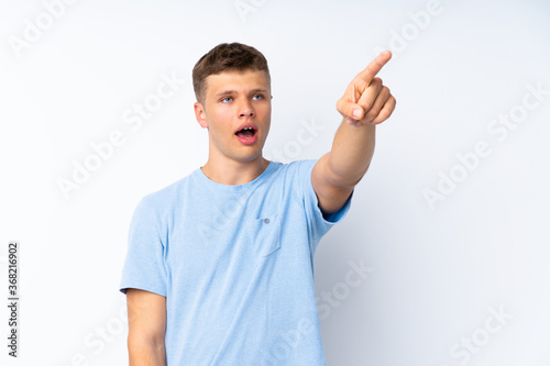 Young handsome man over isolated white background pointing away