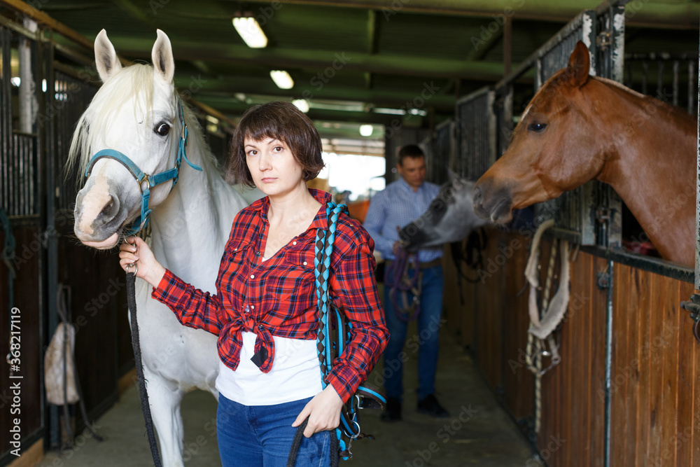 Portrait of woman farm worker standing at horse stable