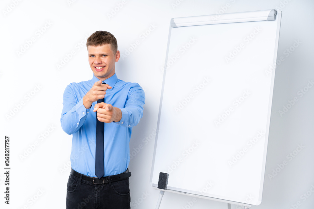 Young businessman giving a presentation on white board points finger at you with a confident expression Young businessman giving a presentation on white board points finger at you with a confident expression