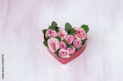 on a pink background a bouquet of pink roses in a gift box in the shape of a heart