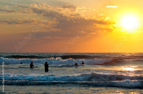 Fototapeta Naklejka Na Ścianę i Meble -  Surfeurs a l’océan face au coucher du soleil