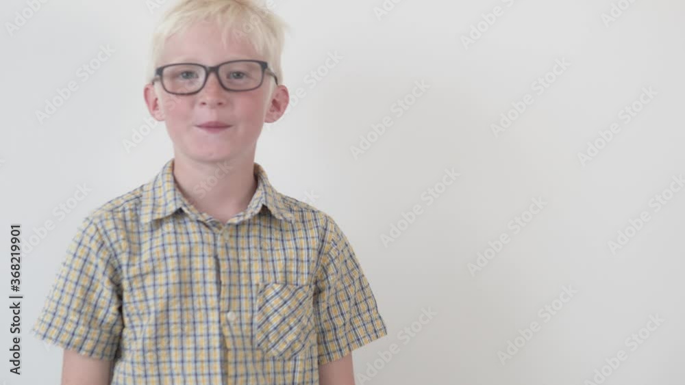 A funny boy with glasses ruffles his hair on his head with his hand ...