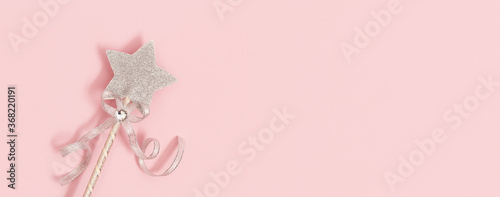 Festive decoration, magic wand, bright silver star with shine on soft pink background with copy space. Minimal holiday concept. Banner for website. photo