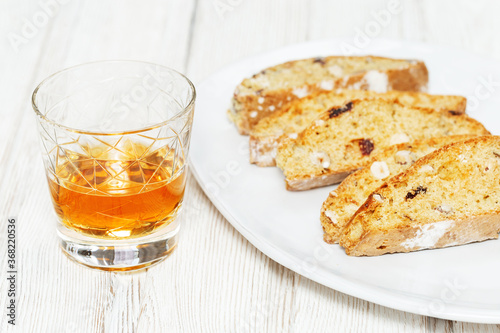 Italian biscotti cookies in white plate and sweet wine Vin Santo.