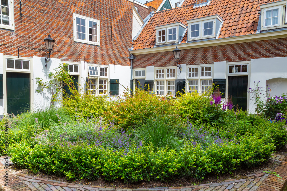Courtyard with colroful garden and small houses in the center of city Leiden in the Netherlands, Europe