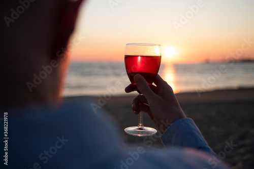 Man with glass of wine on beach at sunset