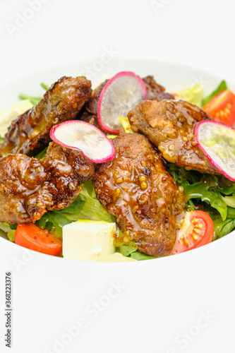 Grilled beef in a sauce with Dejon mustard and soft cheese in a case plate on a gray background.