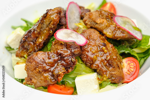 Grilled beef in a sauce with Dejon mustard and soft cheese in a case plate on a gray background.