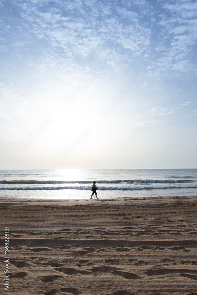 Mujer paseando por la playa al amanecer en verano