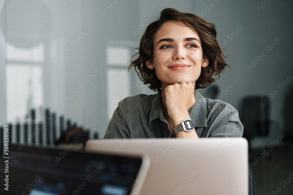 Naklejka premium Image of young beautiful joyful woman smiling while working with laptop