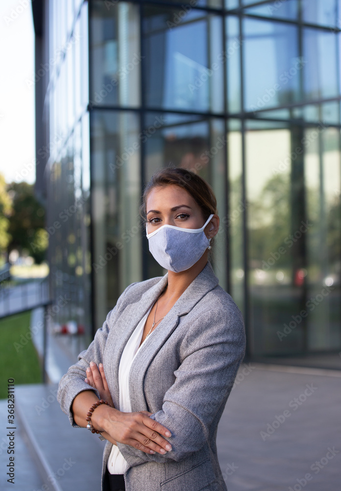 Business woman with protective mask in front of glass building